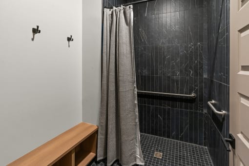 a bathroom with a black tiled shower and a shower curtain