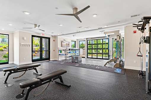 A gym with a bench, weights, and a fan.