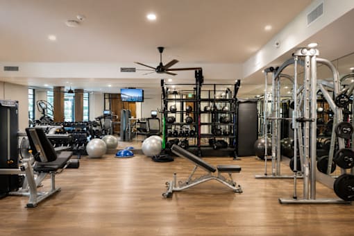 A spacious gym with a variety of equipment and a television.