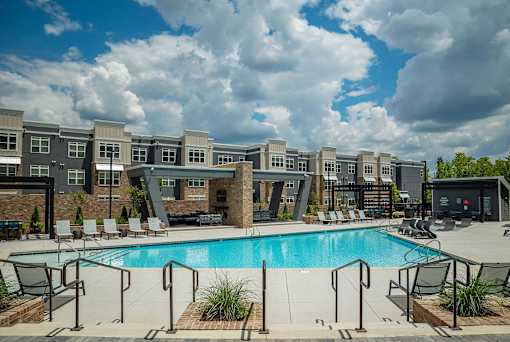A swimming pool surrounded by a metal railing and chairs.