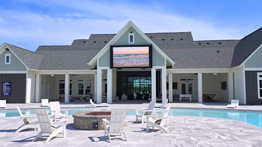 A poolside area with white chairs and a building in the background.