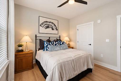 A bedroom with a bed, two lamps, and a ceiling fan.