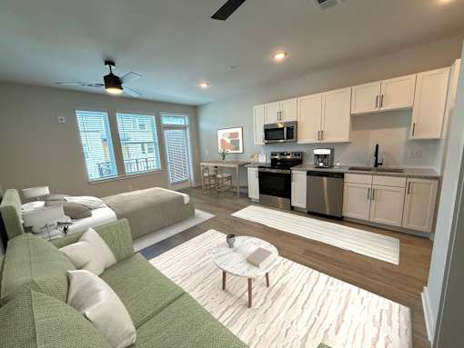 A modern living room with a green couch and a kitchen in the background.