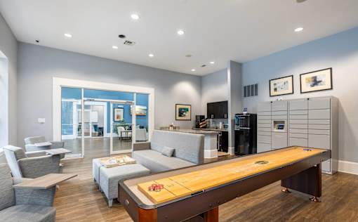 A modern living room with a long wooden table and grey couches.