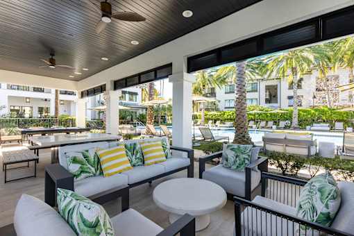 A patio with a white couch and a table with a plant on it.