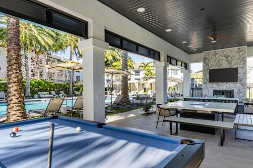 A pool table is in the middle of a patio with a TV and a fireplace.