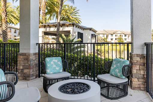 A patio with a fire pit and chairs.