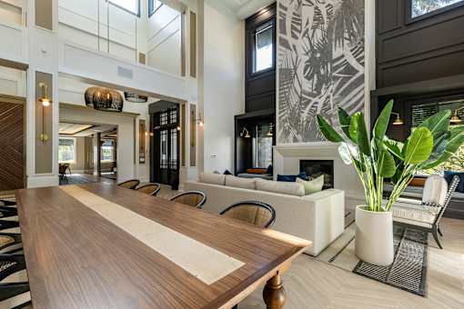 A long wooden table is in the middle of a room with a black and white patterned wall.