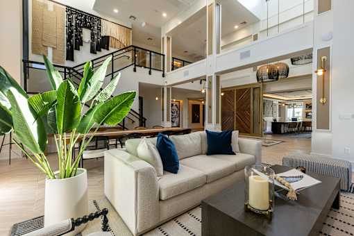 A living room with a couch, a table, and a potted plant.