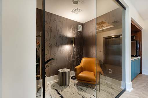 A chair with a black and white patterned cushion is placed in front of a glass wall.