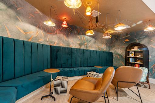 A room with a blue couch, two chairs, and a bookshelf.