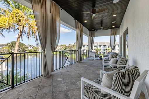 A balcony with a table and chairs overlooking a body of water.
