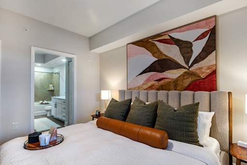 A bedroom with a large bed and a painting on the wall.