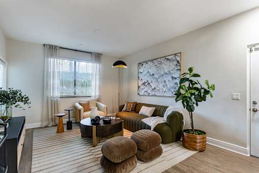 A living room with a brown couch, a coffee table, and a potted plant.