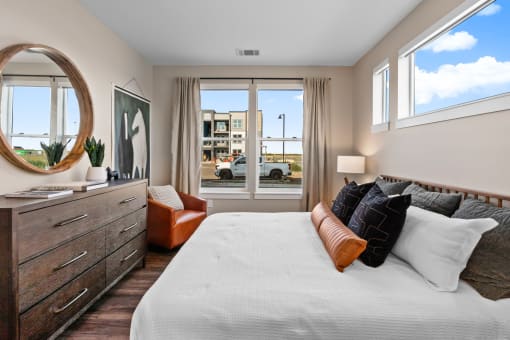 a bedroom with a bed and a dresser and windows
