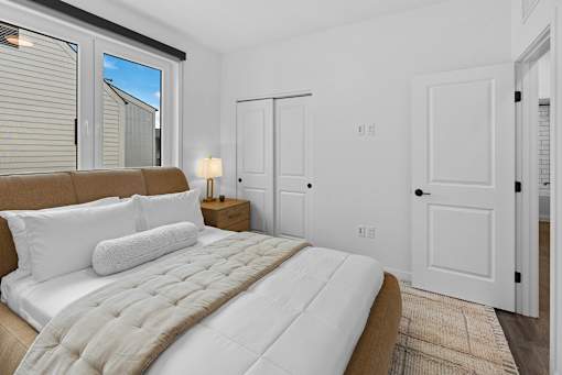 2 Bedroom Townhomes in Bozeman, MT - Highmark Bozeman - Bedroom With Luxury Wood-look Plank Flooring, Area Rug, Bed, Nightstand With Lamp, Closet, And Large Window.