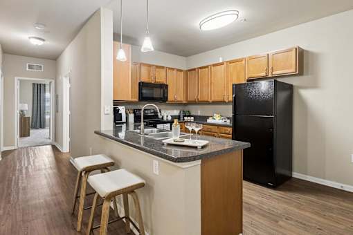 A kitchen with wooden cabinets and a black refrigerator.