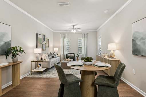 A dining room with a table set for two and a couch in the background.