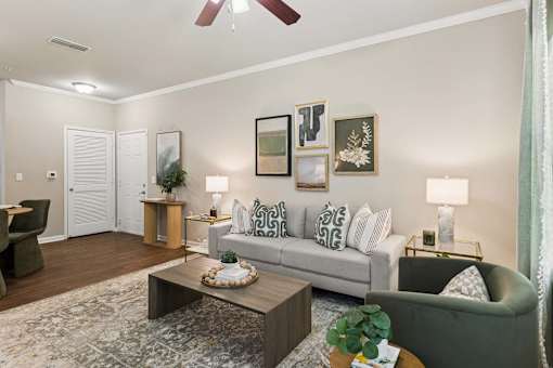 A living room with a grey couch, a coffee table, and a ceiling fan.