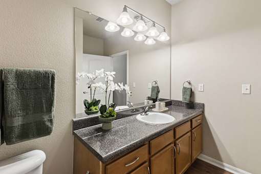 A bathroom with a sink, mirror, and a towel hanging on the wall.