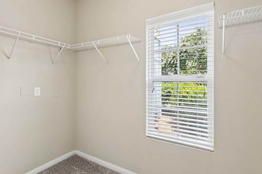 A room with a white wall and a window with blinds.