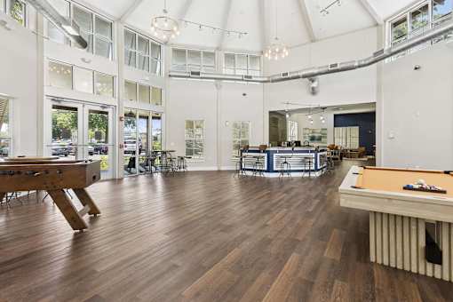 A billiard table is in the middle of a room with a white ceiling and wooden floors.