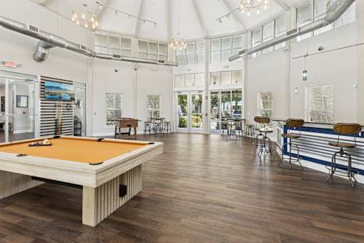 A pool table is in the middle of a room with a bar and a pool table.