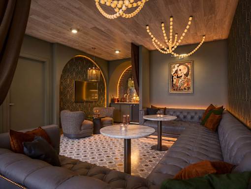 A modern living room with a grey sofa, a round table, and a chandelier.