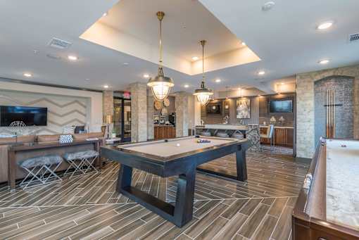 A billiard table is in the middle of a room with a pool table to the right.