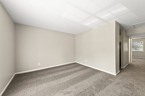 an empty living room with carpet and a door to a hallway