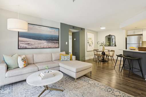 A living room with a white couch and a large landscape painting on the wall.