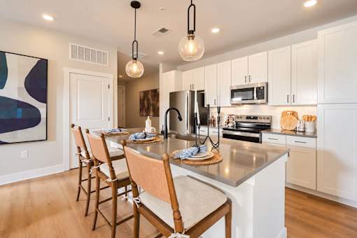 A kitchen with a table set for four with a painting on the wall.