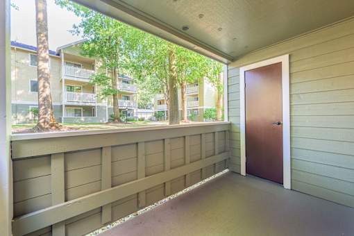 A balcony with a brown door and a view of apartment buildings.