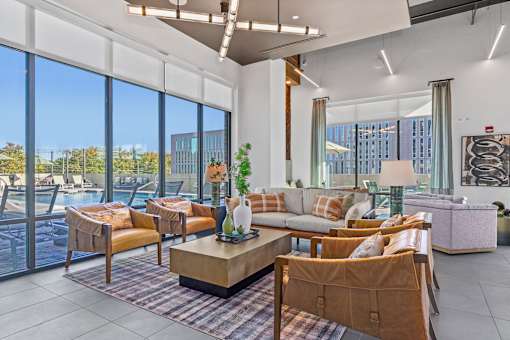 A living room with a large window overlooking a pool and trees.