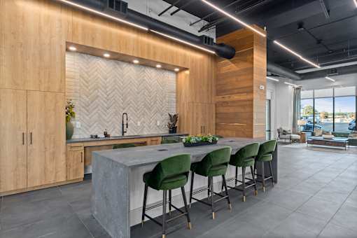 A modern kitchen with a long island and green chairs.