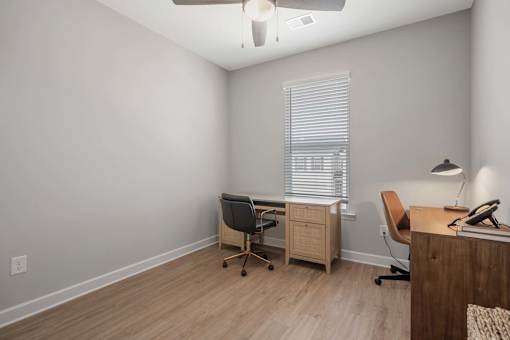 A room with a desk, chair, and a window with blinds.