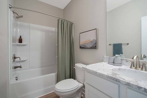 A white bathroom with a toilet, sink, and shower.