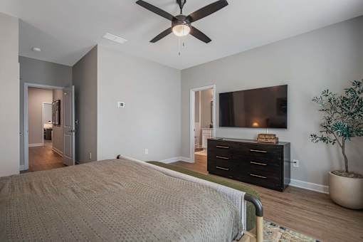 A bedroom with a bed, dresser, and ceiling fan.