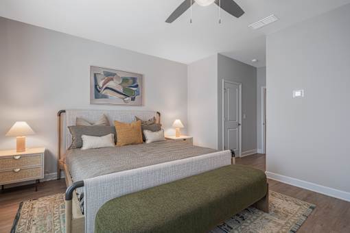 A bedroom with a bed, nightstands, and a painting on the wall.