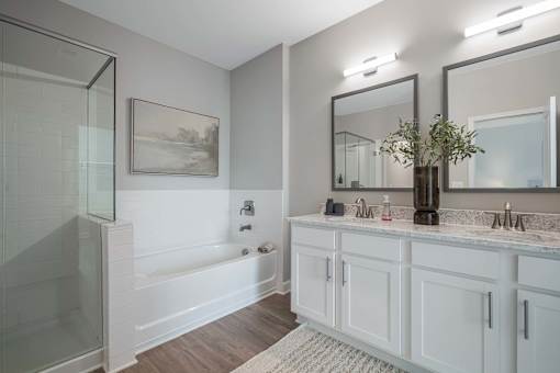 A bathroom with a white tub, sink, and mirror.
