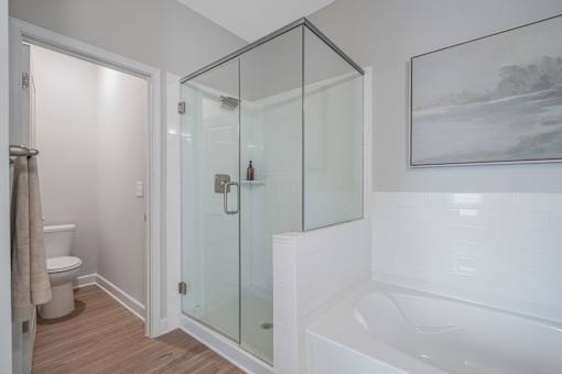 A white bathroom with a glass shower door and a white bathtub.