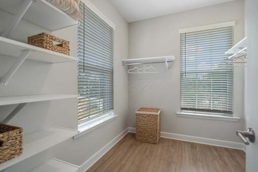 A white closet with a basket on the floor.