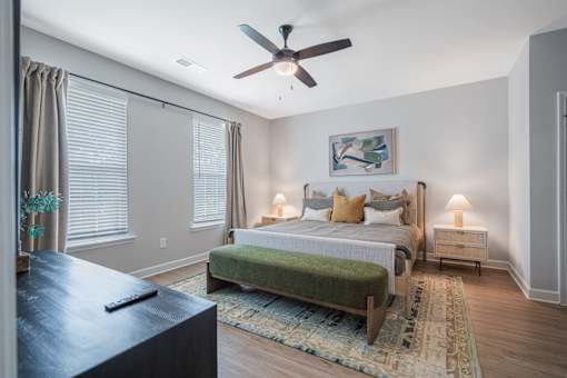 A bedroom with a bed, nightstands, and a ceiling fan.