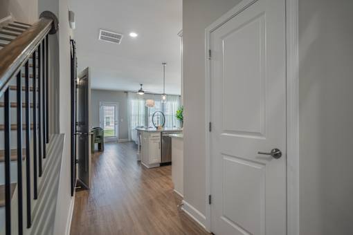 A hallway with a white door and a staircase with black railings.