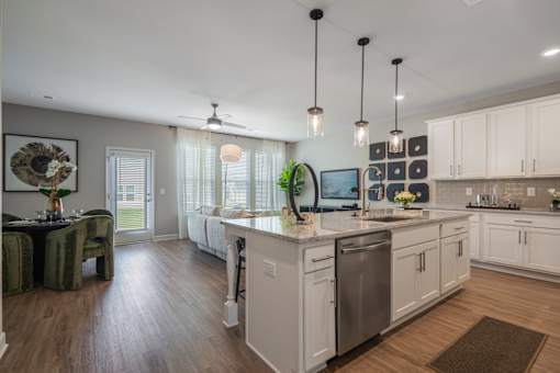 A kitchen with white cabinets and a wooden floor.