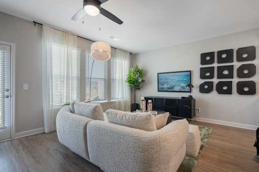 A living room with a large couch and a ceiling fan.