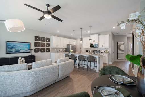 A modern living room with a grey sofa and a dining table set for four.