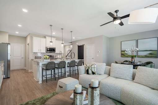 A modern living room with a dining area and kitchen in the background.
