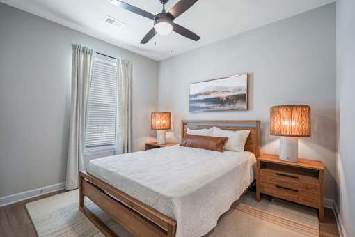 A bedroom with a bed, nightstands, and a ceiling fan.