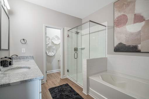 A bathroom with a marble countertop and a glass shower stall.